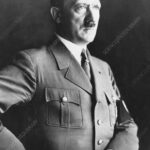 Black and white portrait of a man in a vintage military uniform standing with his hand on his hip and looking off to the right